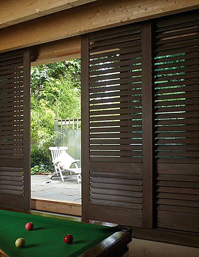 Dark stained sliding shutters opening to a garden room